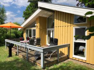 a house with a deck with chairs and an umbrella at Seeschwalbe 240 in Mirow