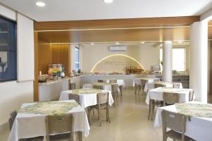 a restaurant with white tables and chairs and a counter at Hotel 2 Gauchos in Naviraí
