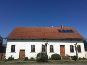 a white house with a red roof with a window at Sommerhof im Havelland in Nennhausen