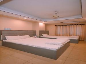 ein Schlafzimmer mit zwei Betten mit weißer Bettwäsche in der Unterkunft Sylhet Hotel Grand Usman in Sylhet