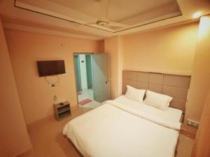ein Schlafzimmer mit einem weißen Bett und einem Spiegel in der Unterkunft Sylhet Hotel Grand Usman in Sylhet