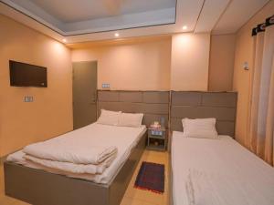 ein Schlafzimmer mit zwei Betten und einem Fernseher an der Wand in der Unterkunft Sylhet Hotel Grand Usman in Sylhet