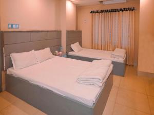 zwei Betten in einem Krankenhauszimmer mit weißen Laken in der Unterkunft Sylhet Hotel Grand Usman in Sylhet