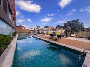 a swimming pool with tables and chairs next to a building at Loft Prime Ribeirão Apogeo in Ribeirão Preto