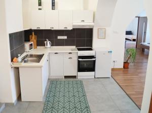 a kitchen with white cabinets and a kitchen rug at Apartment Porta in Terezín