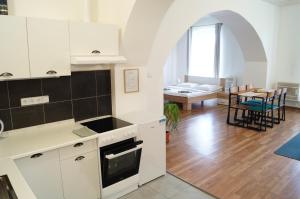 a kitchen with white cabinets and a living room at Apartment Porta in Terezín