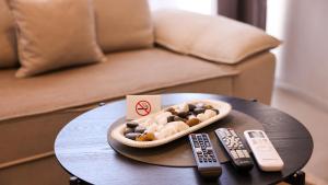 a bowl of rocks on a table with two remote controls at Enzo's Apartments Prishtina in Prishtinë