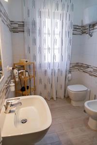a bathroom with a sink and a toilet and a shower curtain at Gli agrumi di Nonna Peppina - Appartamento Limoni in Mondragone +11 photos
