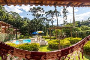 a hammock in a garden with a pool at Pousada Recanto do Pico in Santo Antônio do Pinhal