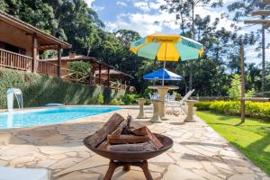 an umbrella and a fire pit next to a pool at Pousada Recanto do Pico in Santo Antônio do Pinhal +10 photos