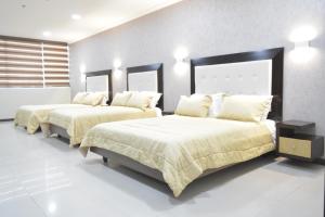 two beds in a bedroom with white walls and white floors at PALMAR CENTER in El Guabo +12 photos
