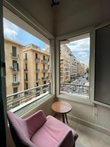 a living room with a pink chair and a large window at Le Caire Guest Houes Cairo in Cairo