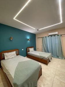 a bedroom with two beds and a blue wall at Le Caire Guest Houes Cairo in Cairo