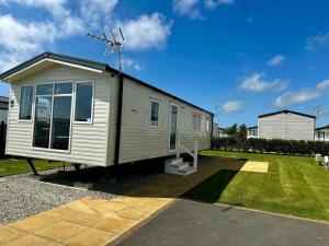a small white tiny house on the side of a yard at Atlantic 63 in Bude