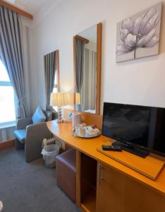 a room with a desk with a television and a living room at The Strand Hotel in Blackpool