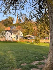 a tree in a field with a house and a church at The Linen Loft - 2 Bed Apartment - Central Town Location - Reserved Parking Space Included in Ross on Wye