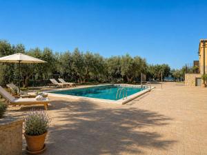 a swimming pool with chairs and an umbrella at L'Albea Hotel Rural in Vall dʼAlba