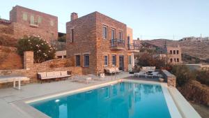 a large swimming pool in front of a building at Cycladic Stone House with Pool & Sunset Views in Gialiskari