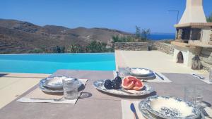 a table with plates of food on top of a patio at Cycladic Stone House with Pool & Sunset Views in Gialiskari