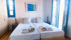 a bedroom with two beds with towels on them at Cycladic Stone House with Pool & Sunset Views in Gialiskari +42 photos
