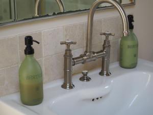 two green bottles are sitting on a bathroom sink at Hobbs Hole Cottage & Studio in Great Tew +94 photos