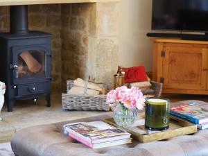 a living room with a fireplace and a table with books at Hobbs Hole Cottage in Great Tew