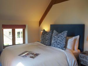 a bedroom with a bed with blue and white pillows at Hobbs Hole Cottage in Great Tew
