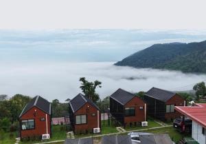 a group of houses in a field with clouds in the background at Heaven Khaokho2 in Khao Kho +16 photos