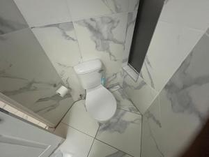 a white bathroom with a toilet and marble walls at Caponero accommodation conference in Welkom