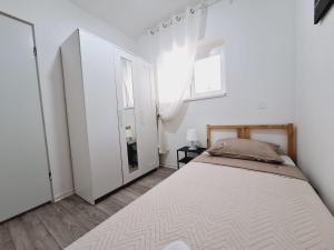 a white bedroom with a bed and a window at Apartment Sia in Jadranovo