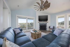a living room with a blue couch and a fireplace at 2934 - Seas the Day in Duck