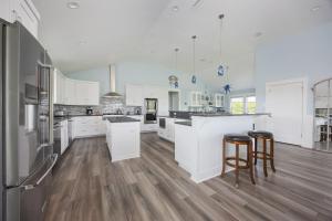 a large kitchen with white cabinets and wooden floors at 2934 - Seas the Day in Duck