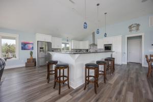 a kitchen with white cabinets and bar stools at 2934 - Seas the Day in Duck +51 photos
