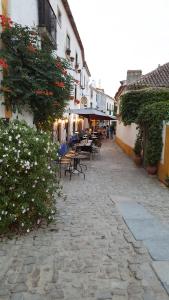 una strada acciottolata con tavoli, sedie e fiori di Casa do Castelo - Óbidos a Óbidos Altre 22 foto