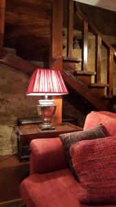 a lamp sitting on a table next to a red couch at Casa do Castelo - Óbidos in Óbidos