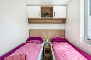 two beds in a small room with pink sheets at Haus Lotte und Frieda in Riedenburg
