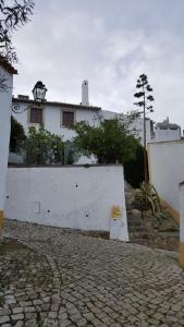 una pared blanca con un banco frente a un edificio en Casa do Castelo - Óbidos en Óbidos