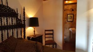 a bedroom with a bed and a chair and a lamp at Casa do Castelo - Óbidos in Óbidos