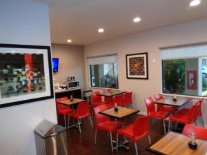 a restaurant with wooden tables and red chairs at Grand Villa Inn Galleria in Houston