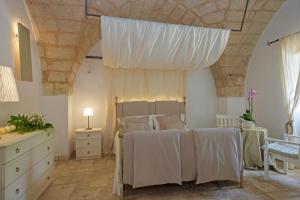 a bedroom with a bed with white sheets and a ceiling at Masseria Pagliamonte in San Vito dei Normanni