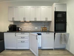 a kitchen with white cabinets and black appliances at Hoovimaja in Pärnu
