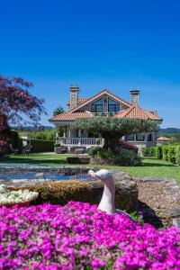 a house with a bird in a garden with pink flowers at Casa Xardín in O Pedrouzo
