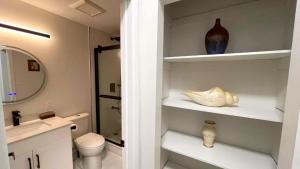 a bathroom with a toilet and a vase on shelves at Queen Boutique Rooms in Toronto