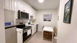 a kitchen with white cabinets and a table and a microwave at Queen Boutique Rooms in Toronto
