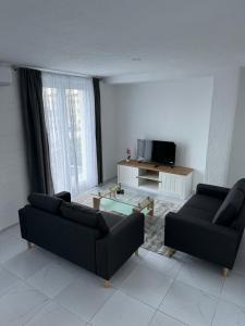 a living room with two black couches and a television at Comfort Days in Gladno Polje