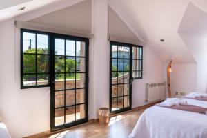 a bedroom with white walls and large windows at Casa Xardín in O Pedrouzo