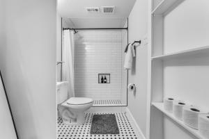a white bathroom with a toilet and a shower at Natural Sabbatical 1 Bedroom Apartment in Dallas +14 photos