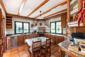a kitchen with wooden cabinets and a white table and chairs at Casa Xardín in O Pedrouzo