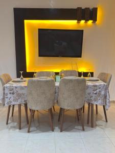 a dining room table with chairs and a television on a wall at corniche d or piscine ferme le lundi in Mohammedia