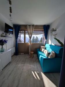 a living room with a blue couch and a window at Le Cocon Bleu in Ustou